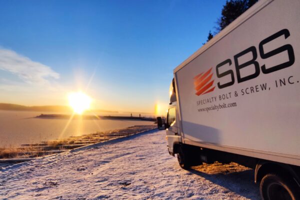 Specialty Bolt & Screw delivery truck in Finland with scenic sunset backdrop.
