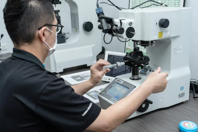 Technician inspecting fasteners under a microscope for quality assurance.