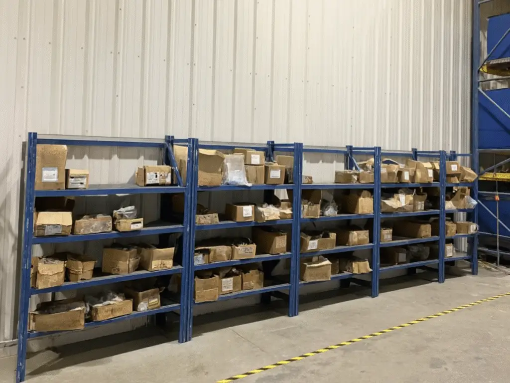 Before photo of warehouse shelving with unsorted fasteners and boxes.